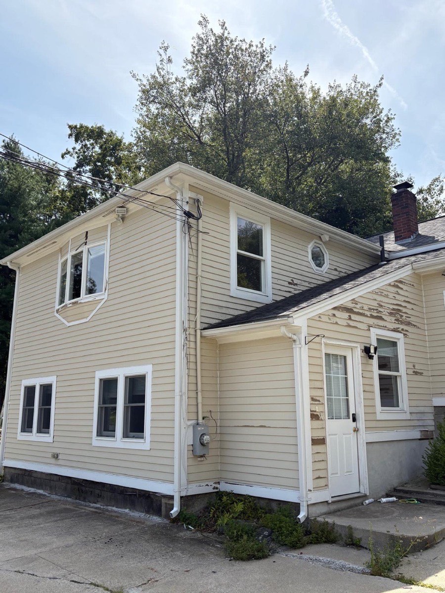Colonial home before painting, peeling cream siding