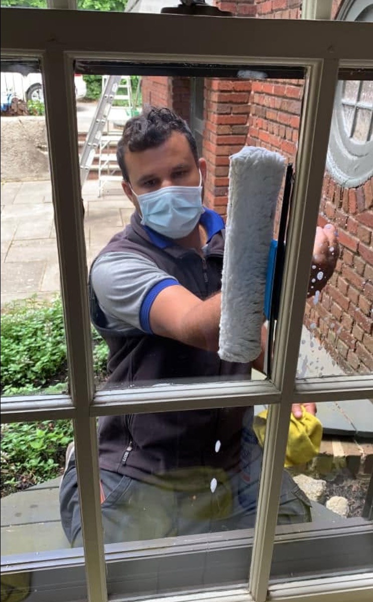 Nat Kay team member washing a window with a professional applicator